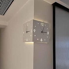 a clock mounted to the side of a wall next to a window with blinds on it