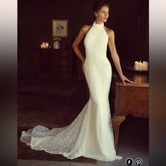 a woman in a white wedding dress standing next to a table with candles on it