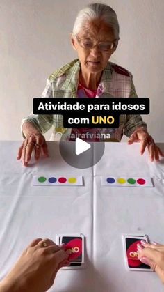 an older woman is playing with cards on the table while another person looks at them