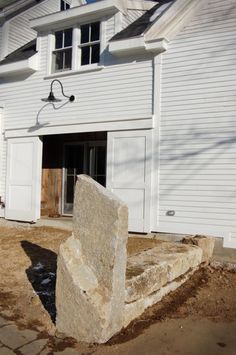 a large rock sitting in front of a white building