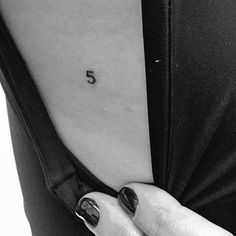 a woman's stomach with the number five tattooed on her lower back and upper arm