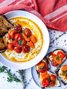 a white plate topped with toasted bread and tomato soup next to slices of garlic bread