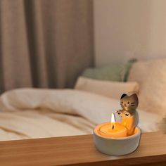 a small cat figurine sitting on top of a table next to a candle