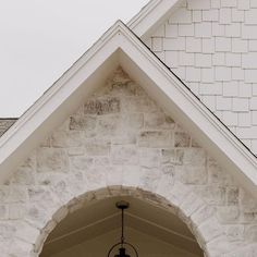 a light hanging from the side of a white brick building next to a clock tower