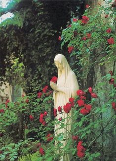 a statue is surrounded by flowers and greenery