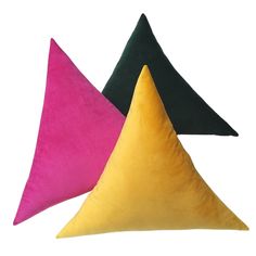 three different colored pillows sitting next to each other on a white surface with one black, one pink and one yellow