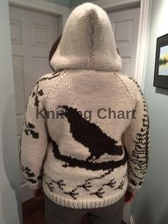 a person standing in front of a door wearing a sweater with a bird on it