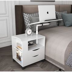 a bed with a laptop on top of it next to a night stand and nightstand