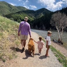 a man and two children walking down a path with a dog