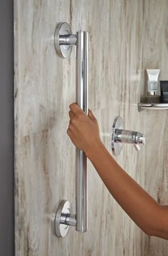 a person's hand is on the handle of a shower faucet