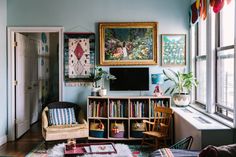 a living room filled with lots of furniture and paintings on the wall next to a window