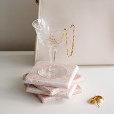 a stack of pink marble coasters next to a small gold - plated ring