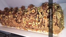 a large piece of cake with nuts and chocolate frosting on it's side