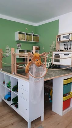 a stuffed animal in a trash can on top of a kitchen counter with lots of toys