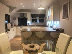 a glass table with four chairs around it in the middle of a large kitchen area