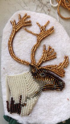 beaded deer ornament on white cloth with green and gold trimmings