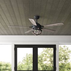 a ceiling fan is hanging from the ceiling in a room with large windows and black doors