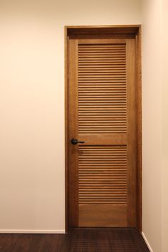 an empty room with a wooden door and hard wood flooring