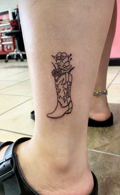 a woman's foot with a tattoo on it that has flowers in the boot