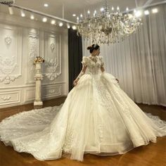 a woman in a white wedding dress standing next to a chandelier