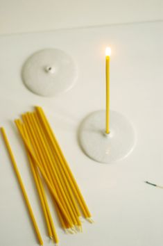 two candles and some straws on a white surface with one candle in the middle