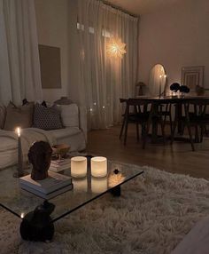 a living room filled with furniture and candles on top of a coffee table in front of a window