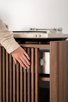 a person is reaching into a cabinet with a turntable on it and there are other things in the background