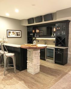 a kitchen with an island and bar stools next to the counter top in front of it