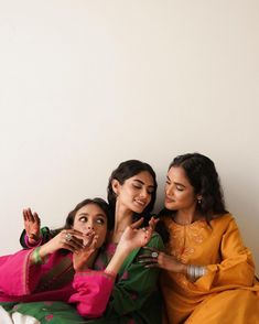 three women sitting next to each other with their hands in the air