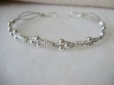 a close up of a silver bracelet on a white surface