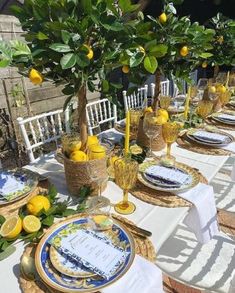 an outdoor table set with lemons and plates