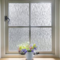 a vase with flowers in it sitting on a window sill next to a cup