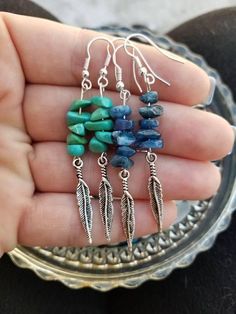 a person is holding some kind of earrings in their hand with beads and feathers on them