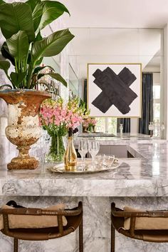 a marble dining room table with two vases and flowers on it, surrounded by chairs