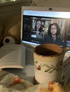 an open laptop computer sitting on top of a desk next to a cup of coffee