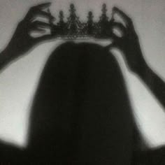 the shadow of a person holding a tiara over their head in front of them