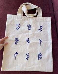 a hand holding a white bag with blue flowers on it