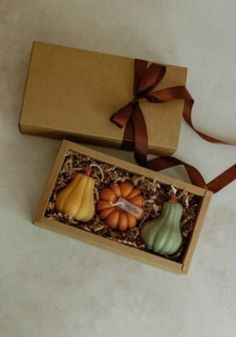 two small pumpkins in a box with a brown ribbon