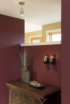 two candles are on the wall next to a vase with some plants