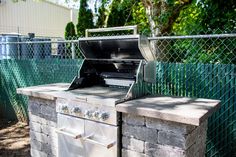 an outdoor bbq grill in front of a chain link fence