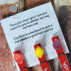 three pieces of red and yellow clothes pins sitting on top of a piece of paper