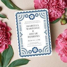 wedding card with blue border and pink flowers on table next to paper cutout save the date