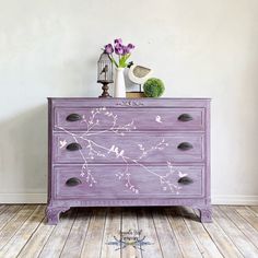 a purple painted dresser with flowers on it