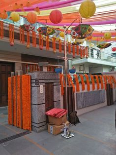 orange and yellow decorations are hanging from the ceiling in an indoor area that is decorated with paper lanterns