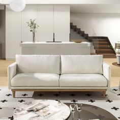 a living room with a white couch and coffee table in front of the stairs leading up to an open floor plan