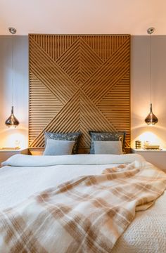 a bed with two lamps on either side of it and a blanket on the headboard