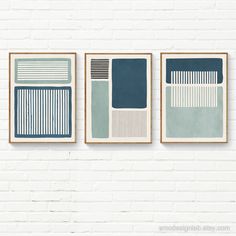 three framed art pieces on a white brick wall, each with different shades of blue