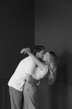 black and white photograph of a man kissing a woman's head in an empty room