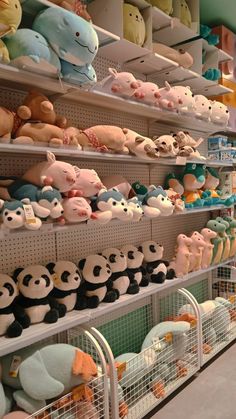 many stuffed animals are on shelves in a store