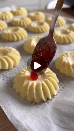 a spoon is being used to dip some food into the batter on top of buns